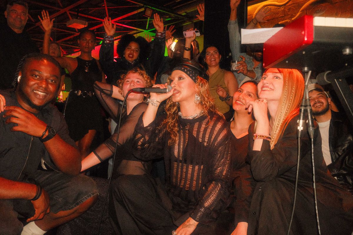 Person performs energetically on stage at a bar, captivating the audience with her vocals.
